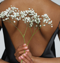 woman shown from back with hands behind her back holding flowers